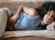 Karın ağrısı nedeniyle uzanan kadın
